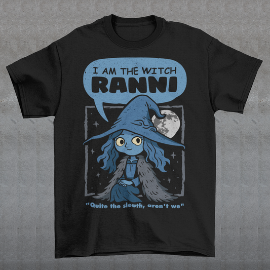 Black t-shirt featuring a cute blue witch character with large eyes wearing a pointed hat and cloak, set against a night sky with a full moon and stars. Text above reads “I AM THE WITCH RANNI,” with a smaller quote below saying “Quite the sleuth, aren’t we.” The design has a dark fantasy, game-inspired style with soft blue tones and a whimsical, mystical aesthetic.