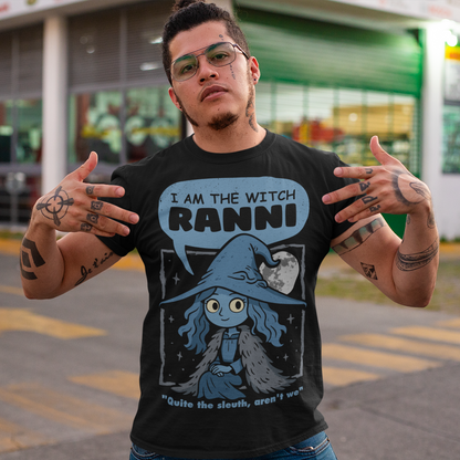 Black t-shirt featuring a cute blue witch character with large eyes wearing a pointed hat and cloak, set against a night sky with a full moon and stars. Text above reads “I AM THE WITCH RANNI,” with a smaller quote below saying “Quite the sleuth, aren’t we.” The design has a dark fantasy, game-inspired style with soft blue tones and a whimsical, mystical aesthetic.
