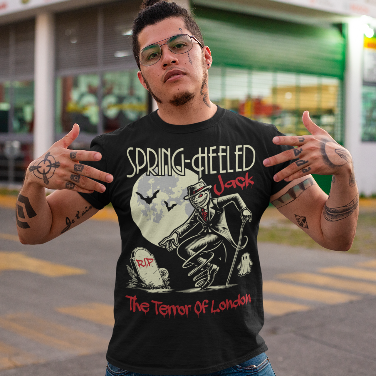 Black t-shirt of Spring-heeled Jack beside a tombstone with a ghost on the other side. Text above SPRING-HEELED JACK.