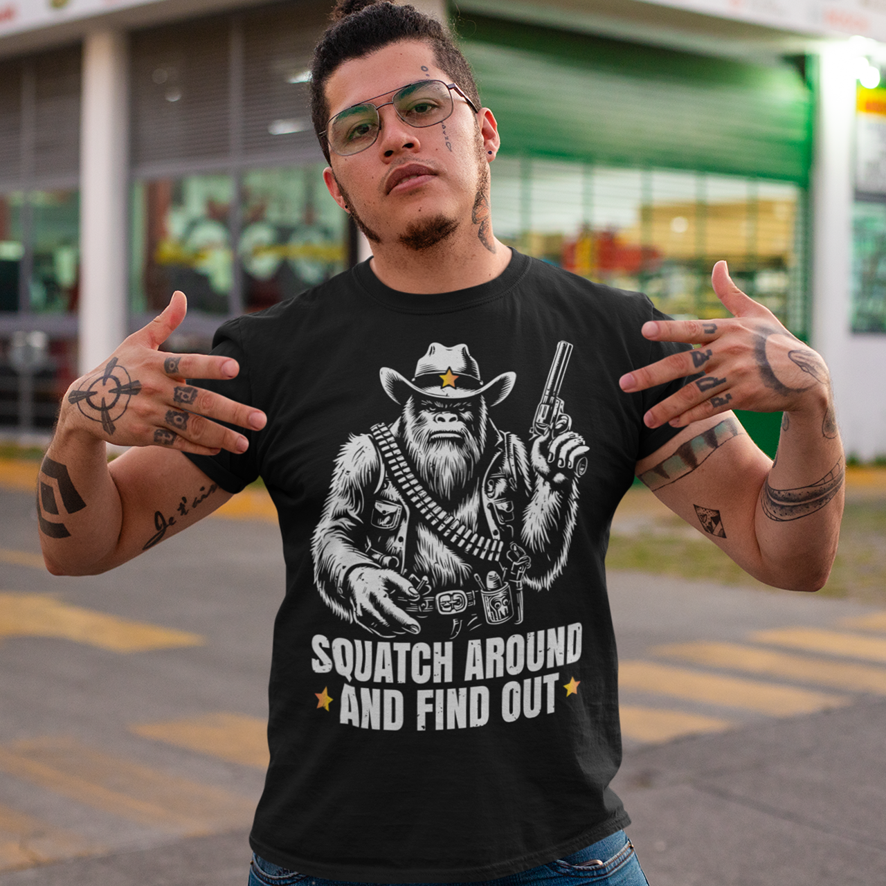 Black t-shirt of a sheriff Sasquatch in the wild west holding a gun with text underneath SQUATCH AROUND AND FIND OUT.