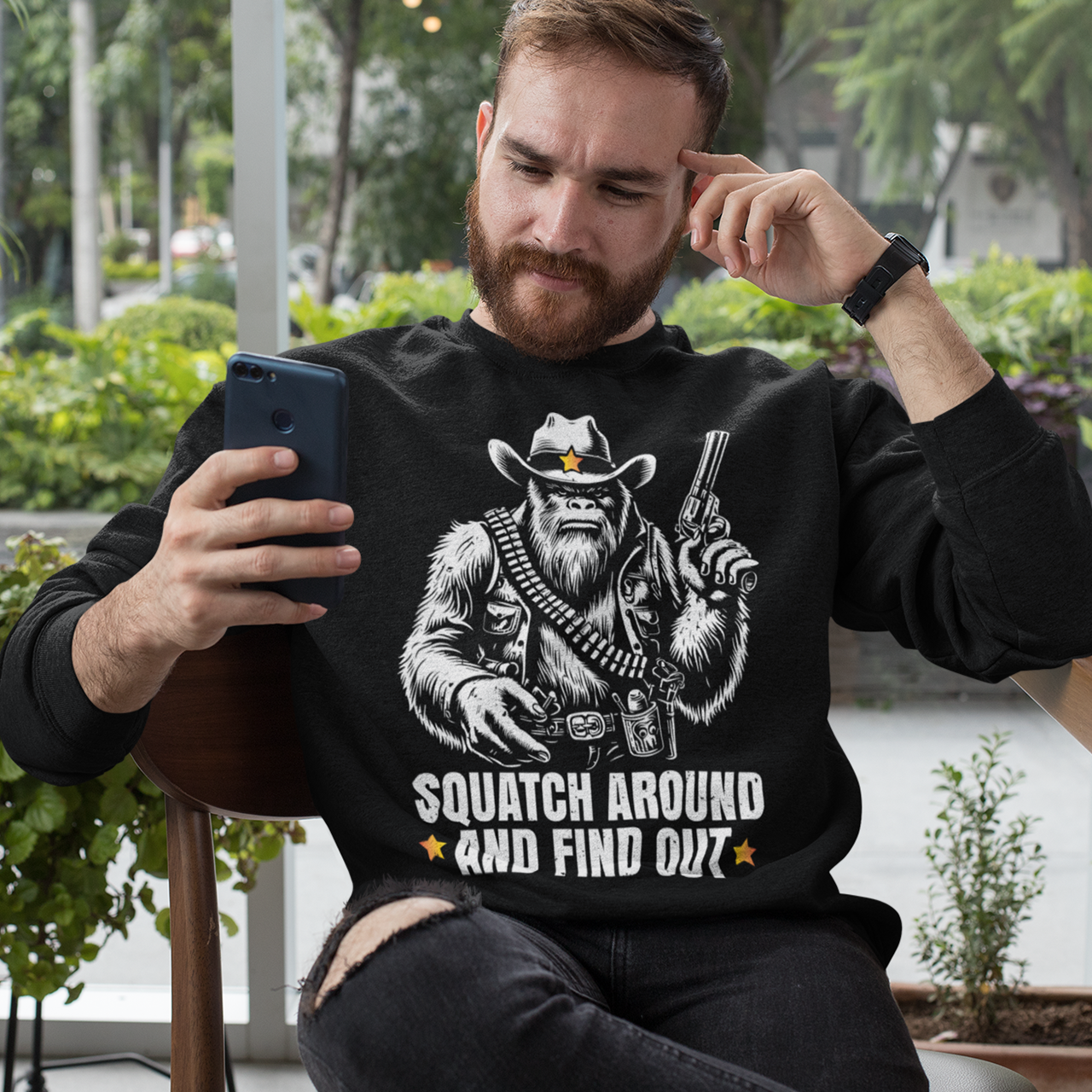 Black sweatshirt of a sheriff Sasquatch in the wild west holding a gun with text underneath SQUATCH AROUND AND FIND OUT.