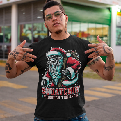 Get ready for holiday fun with our "Squatchin' Through the Snow" T-Shirt! This festive design features a whimsical Santa Sasquatch, decked out in a red Santa hat, strolling through a snowy forest. With his massive feet leaving tracks behind, he's the perfect mix of holiday spirit and mysterious wilderness charm.