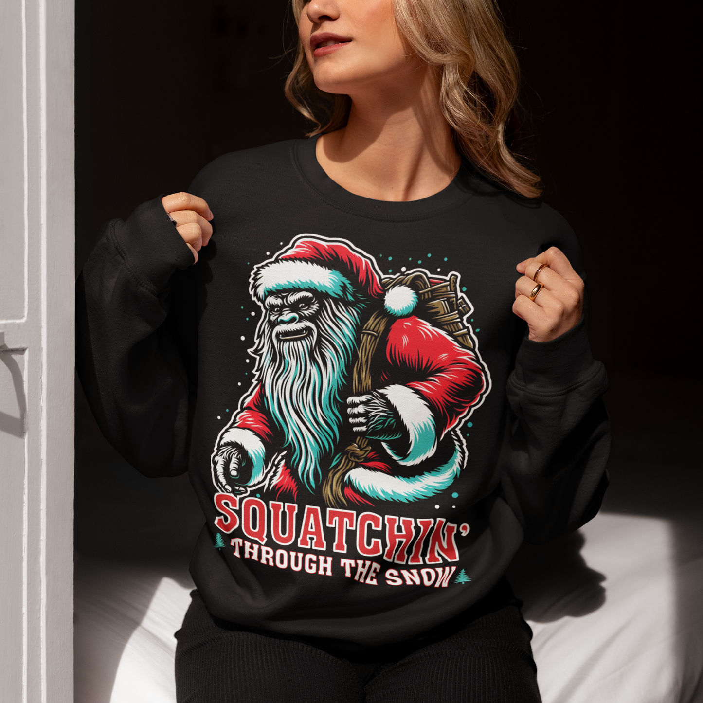 Black Christmas sweatshirt of a Santa sasquatch and text "Squatchin' through the snow."