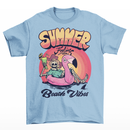 Light blue t-shirt of a skeleton floating on a rubber flamingo in the sea with a cocktail and cigar in front of a sunset with text "SUMMER FEELING BEACH VIBES".