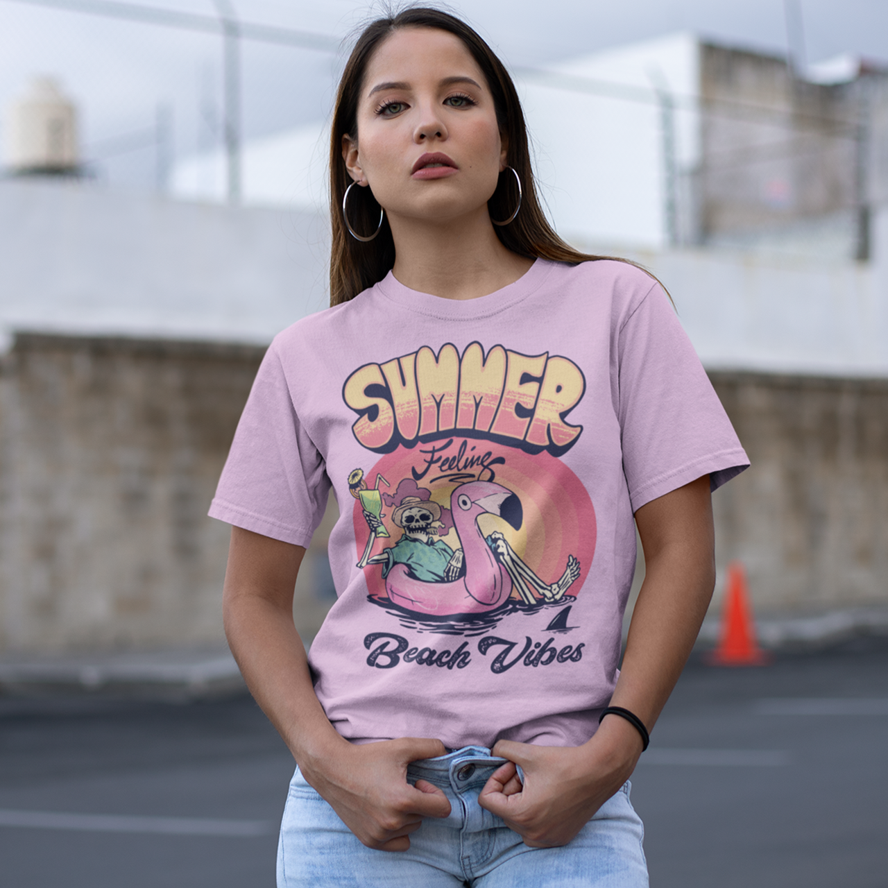 Pink t-shirt of a skeleton floating on a rubber flamingo in the sea with a cocktail and cigar in front of a sunset with text "SUMMER FEELING BEACH VIBES".