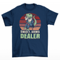 Navy t-shirt of a mafia T-Rex in a suit sitting on a chair with a retro sun background with text underneath "SMALL ARMS DEALER".