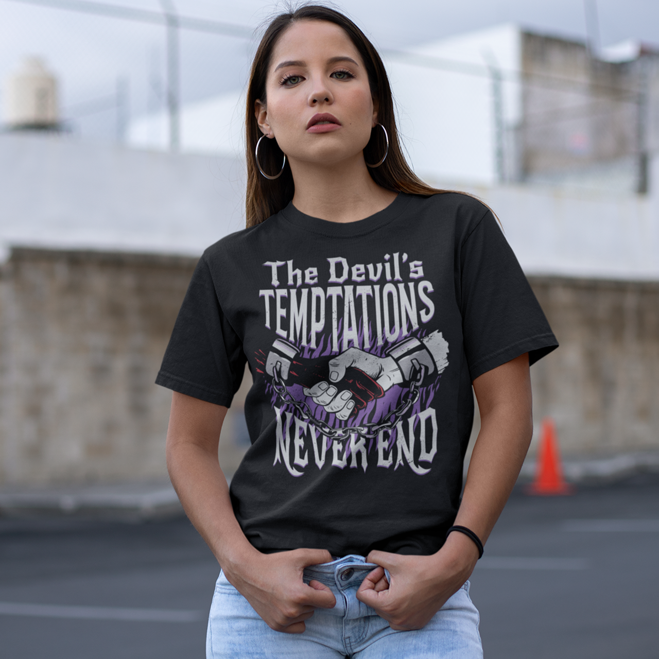 Black t-shirt with a hand shaking the devils hand in chains with text "THE DEVILS TEMPTATIONS NEVER END".