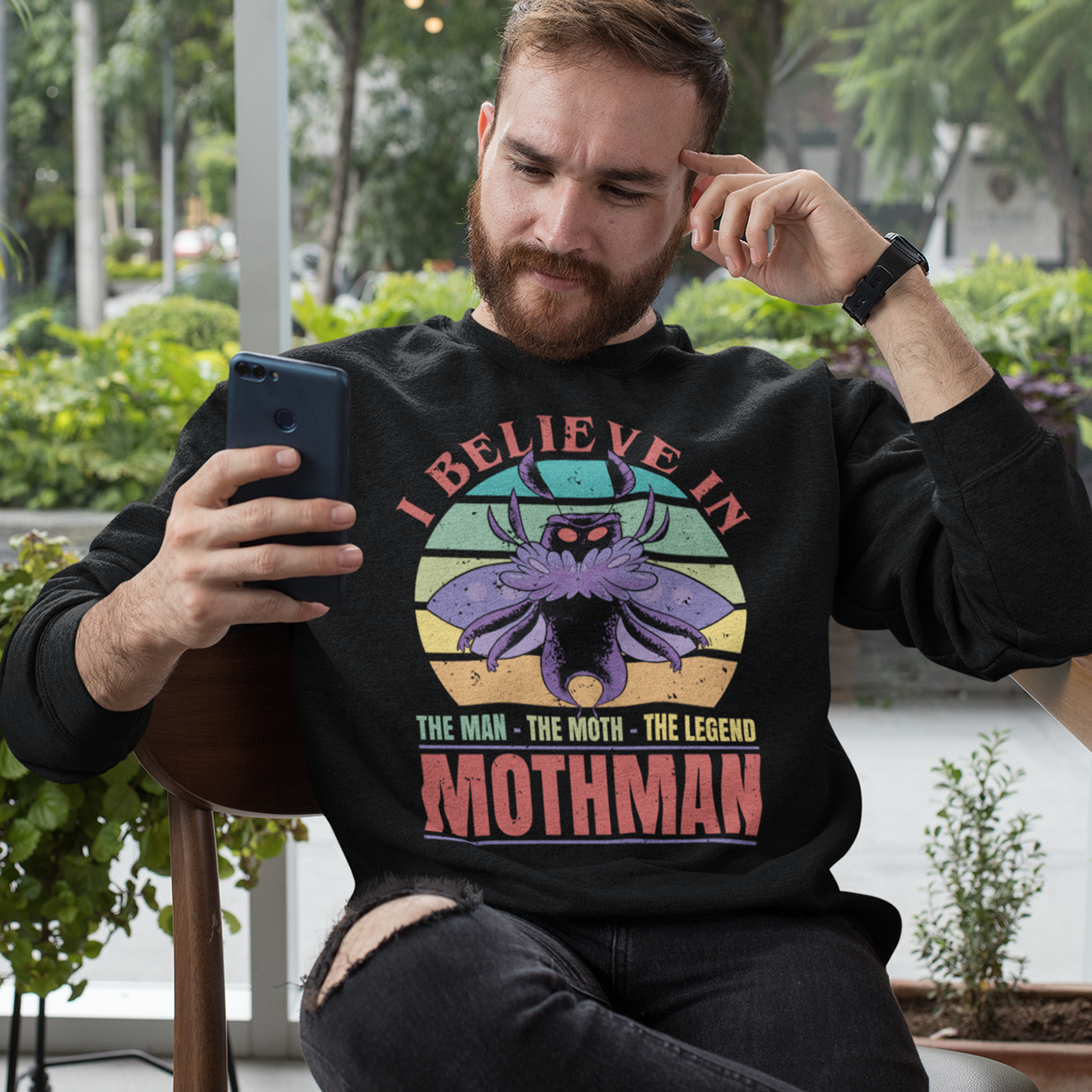 Black sweatshirt of Mothman with a retro sun background with text "THE MAN THE MOTH THE LEGEND".