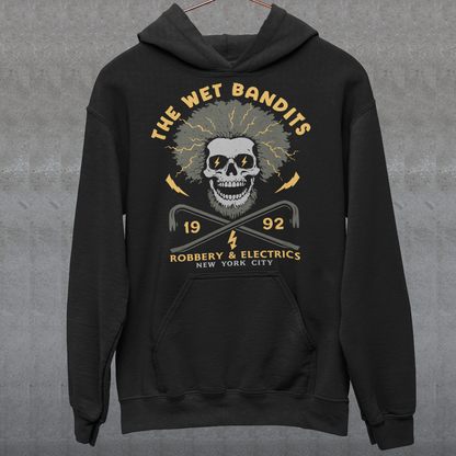 Shock your style to life with this “The Wet Bandits – Robbery And Electrics” hoodie! Featuring a bold skull design with wild electric hair, crossed crowbars, and vintage lettering, this tee blends rock-n-roll attitude with classic movie nostalgia. Inspired by the unforgettable duo from the holiday favorite, it’s perfect for fans who love edgy humor and retro vibes.