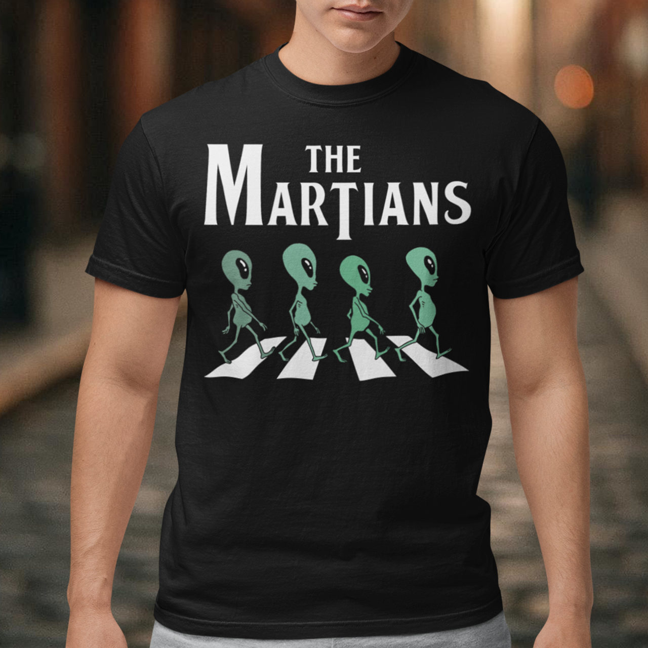 "Step into the extraterrestrial realm with our exclusive 'THE MARTIANS' t-shirt. This eye-catching design showcases four uniquely crafted aliens confidently crossing a road, adding a touch of whimsy and intrigue to your style. Printed with vibrant colors and intricate details, this shirt sparks curiosity about what lies beyond our planet. Embrace a blend of cosmic charm and playful imagination with 'THE MARTIANS' tee, inviting conversation and celebrating the mysteries of the universe in style."