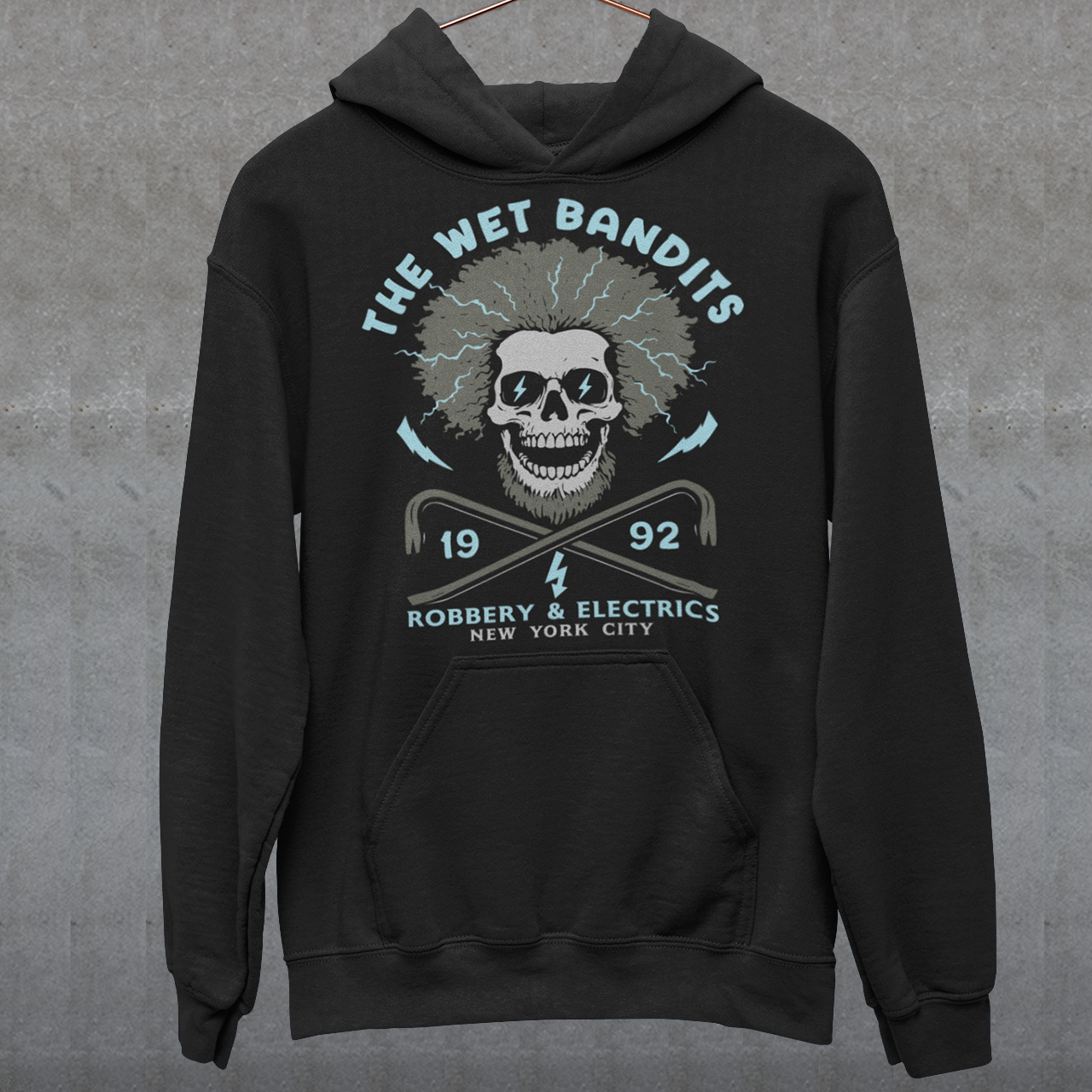 Shock your style to life with this “The Wet Bandits – Robbery And Electrics” hoodie! Featuring a bold skull design with wild electric hair, crossed crowbars, and vintage lettering, this tee blends rock-n-roll attitude with classic movie nostalgia. Inspired by the unforgettable duo from the holiday favorite, it’s perfect for fans who love edgy humor and retro vibes.