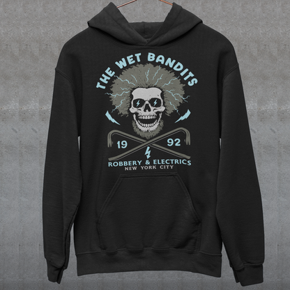 Shock your style to life with this “The Wet Bandits – Robbery And Electrics” hoodie! Featuring a bold skull design with wild electric hair, crossed crowbars, and vintage lettering, this tee blends rock-n-roll attitude with classic movie nostalgia. Inspired by the unforgettable duo from the holiday favorite, it’s perfect for fans who love edgy humor and retro vibes.