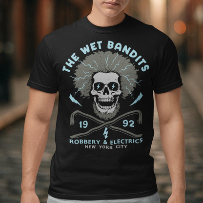 Shock your style to life with this “The Wet Bandits – Robbery And Electrics” t-shirt! Featuring a bold skull design with wild electric hair, crossed crowbars, and vintage lettering, this tee blends rock-n-roll attitude with classic movie nostalgia. Inspired by the unforgettable duo from the holiday favorite, it’s perfect for fans who love edgy humor and retro vibes.