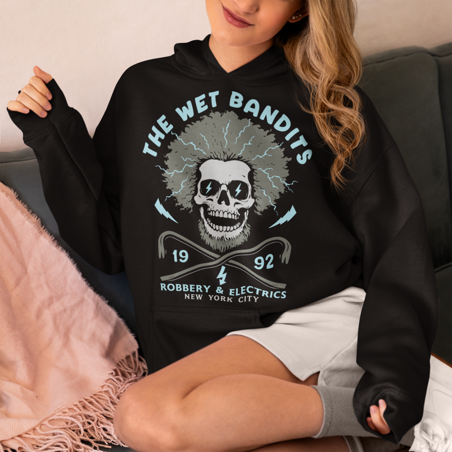 Shock your style to life with this “The Wet Bandits – Robbery And Electrics” hoodie! Featuring a bold skull design with wild electric hair, crossed crowbars, and vintage lettering, this tee blends rock-n-roll attitude with classic movie nostalgia. Inspired by the unforgettable duo from the holiday favorite, it’s perfect for fans who love edgy humor and retro vibes.