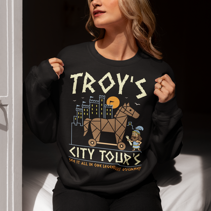 Black sweatshirt featuring a colorful “TROY’S CITY TOURS” graphic with a stylized Trojan horse rolling through an ancient city at sunset. The design includes a small cartoon Trojan warrior and the phrase “SEE IT ALL IN ONE LEGENDARY JOURNEY.” A fun ancient history and Greek mythology themed shirt for history buffs, mythology fans, travelers, and archaeology enthusiasts.