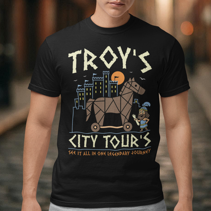 Black t-shirt featuring a colorful “TROY’S CITY TOURS” graphic with a stylized Trojan horse rolling through an ancient city at sunset. The design includes a small cartoon Trojan warrior and the phrase “SEE IT ALL IN ONE LEGENDARY JOURNEY.” A fun ancient history and Greek mythology themed shirt for history buffs, mythology fans, travelers, and archaeology enthusiasts.