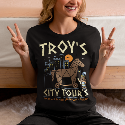 Black t-shirt featuring a colorful “TROY’S CITY TOURS” graphic with a stylized Trojan horse rolling through an ancient city at sunset. The design includes a small cartoon Trojan warrior and the phrase “SEE IT ALL IN ONE LEGENDARY JOURNEY.” A fun ancient history and Greek mythology themed shirt for history buffs, mythology fans, travelers, and archaeology enthusiasts.