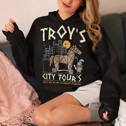 Black hoodie featuring a colorful “TROY’S CITY TOURS” graphic with a stylized Trojan horse rolling through an ancient city at sunset. The design includes a small cartoon Trojan warrior and the phrase “SEE IT ALL IN ONE LEGENDARY JOURNEY.” A fun ancient history and Greek mythology themed shirt for history buffs, mythology fans, travelers, and archaeology enthusiasts.