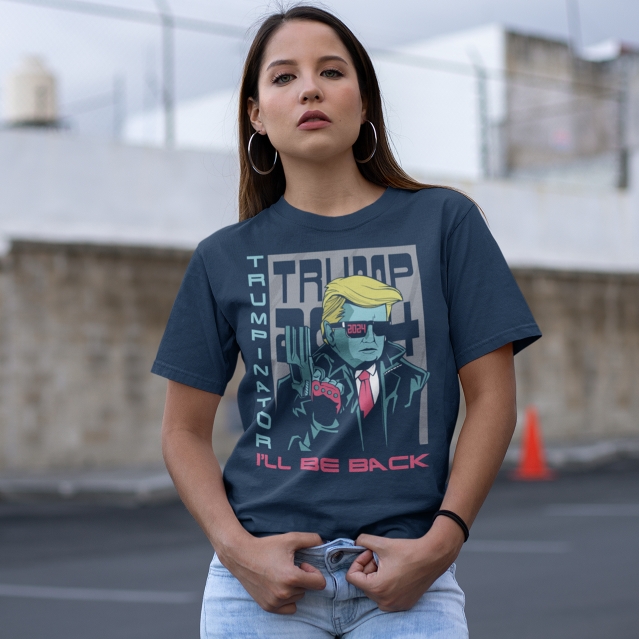 Navy t-shirt of Donald Trump in front of a TRUMP 2024 poster wearing sunglasses and holding a gun with text on the side "TRUMPINATOR" and text underneath "I'LL BE BACK".