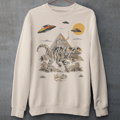 Cream sweatshirt with a skeleton riding a mummy dinosaur in ancient Egypt with UFO and bigfoot walking in the background.