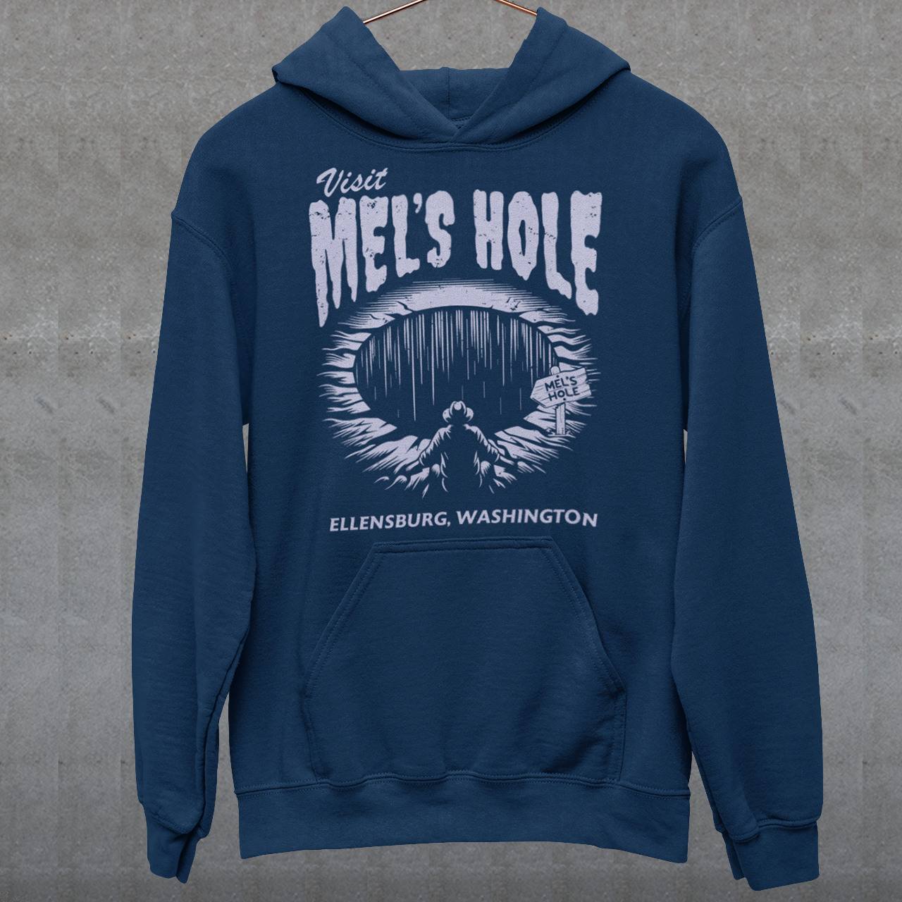 Step into the strange with this quirky and mysterious hoodie! Featuring a bold illustration of a curious man peering into a dark, bottomless abyss, this hoodie pays homage to the legendary paranormal tale of Mel's Hole — a supposed infinite pit in the wilds of Washington State. The vintage-style artwork is topped with the eerie invitation: "VISIT MEL'S HOLE" in retro tourism font, blending humor, folklore, and a dash of the unexplained.