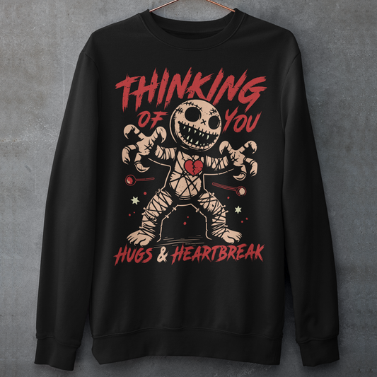 Dark humor meets twisted sweetness with this bold sweatshirt. Featuring a stitched-up voodoo doll at the center, the design captures that perfect mix of love and pain. Above the doll, the phrase “THINKING OF YOU” adds a playful sting, while below, “HUGS &amp; HEARTBREAK” ties it all together with equal parts irony and affection. Perfect for anyone who loves edgy, alternative fashion—or just wants to send a cheeky message without saying a word.
