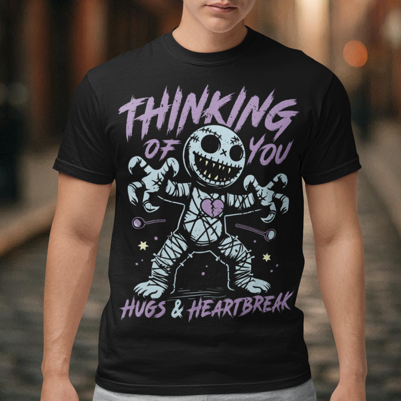 Dark humor meets twisted sweetness with this bold tee. Featuring a stitched-up voodoo doll at the center, the design captures that perfect mix of love and pain. Above the doll, the phrase “THINKING OF YOU” adds a playful sting, while below, “HUGS & HEARTBREAK” ties it all together with equal parts irony and affection. Perfect for anyone who loves edgy, alternative fashion—or just wants to send a cheeky message without saying a word.
