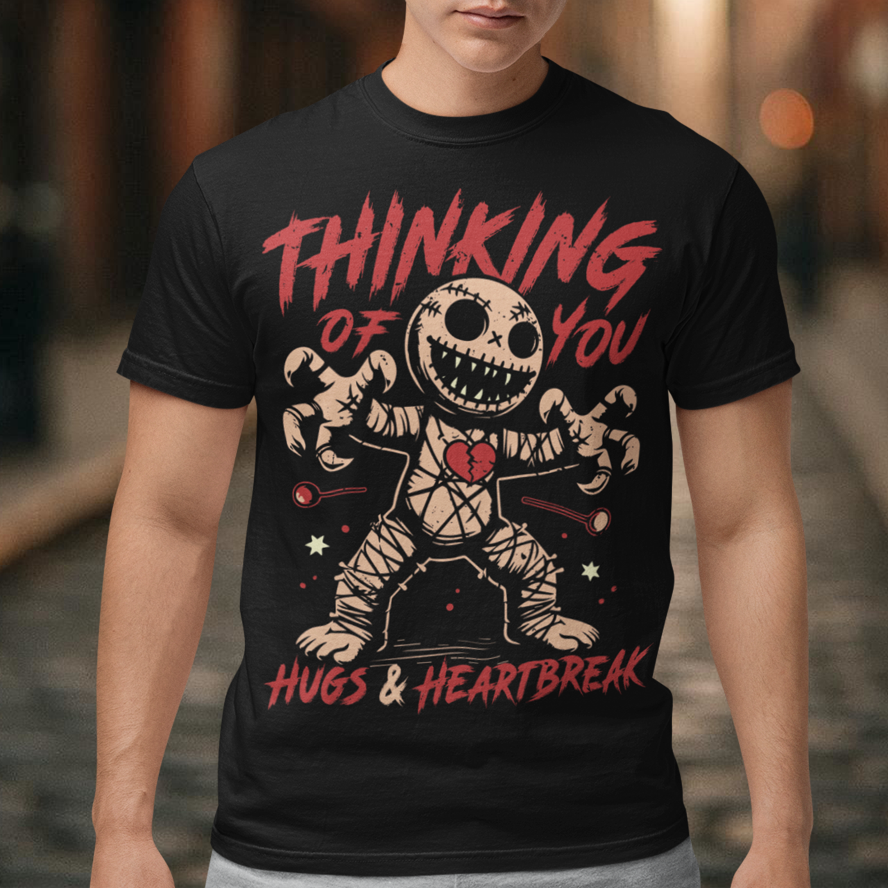 Dark humor meets twisted sweetness with this bold tee. Featuring a stitched-up voodoo doll at the center, the design captures that perfect mix of love and pain. Above the doll, the phrase “THINKING OF YOU” adds a playful sting, while below, “HUGS & HEARTBREAK” ties it all together with equal parts irony and affection. Perfect for anyone who loves edgy, alternative fashion—or just wants to send a cheeky message without saying a word.