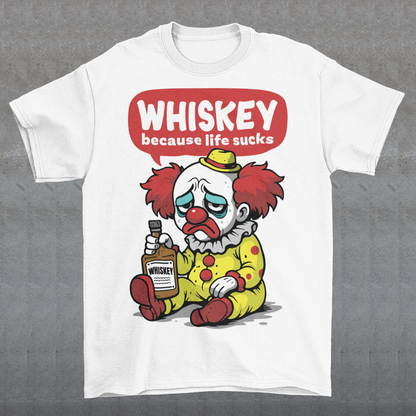 White t-shirt featuring a sad cartoon clown with messy red hair and a tired expression, sitting on the ground holding a bottle labeled whiskey. Above the character, bold text reads “Whiskey because life sucks.” The design combines dark humor with a playful cartoon style, creating a sarcastic and slightly edgy visual.